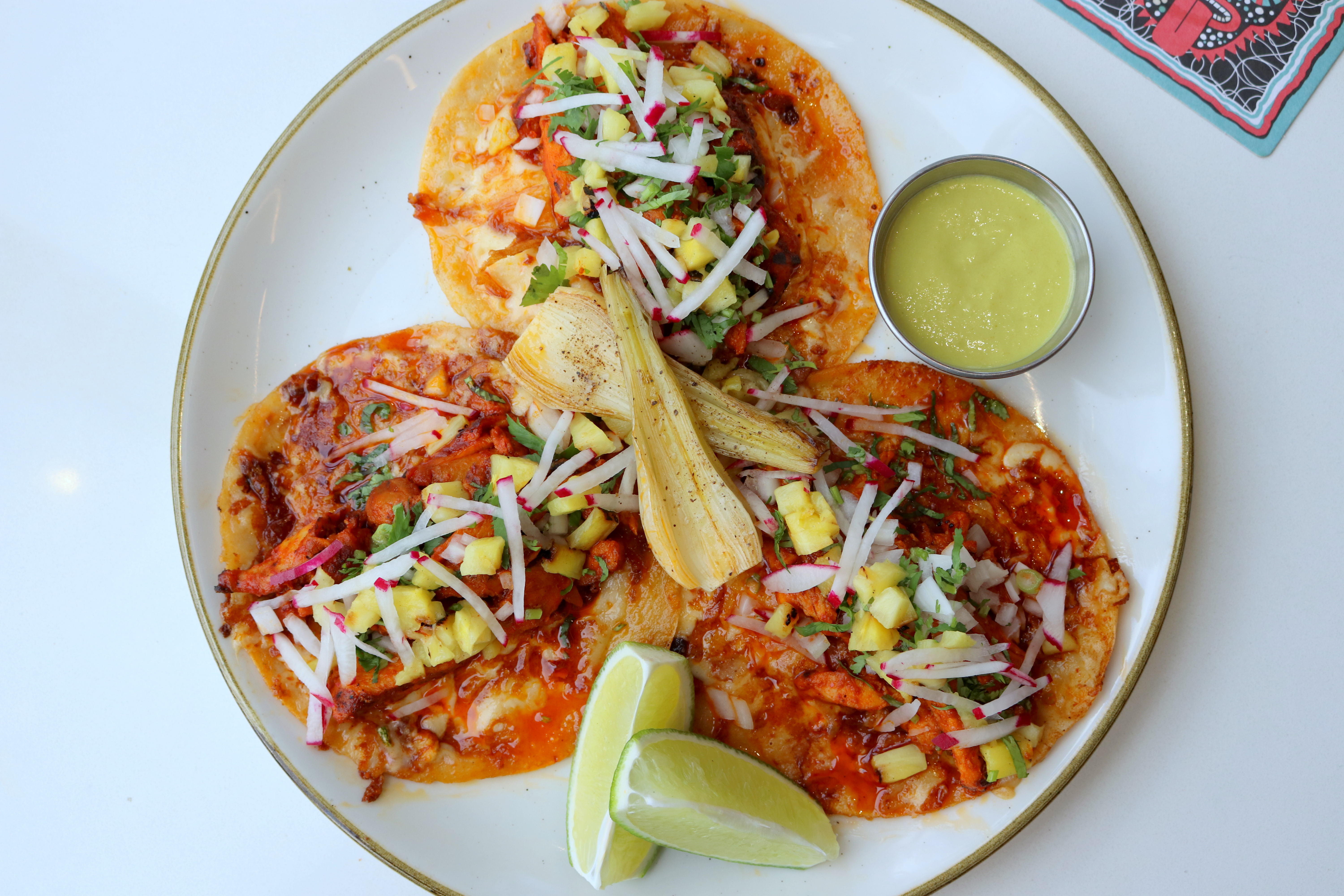 a plate of tacos with sauce and limes