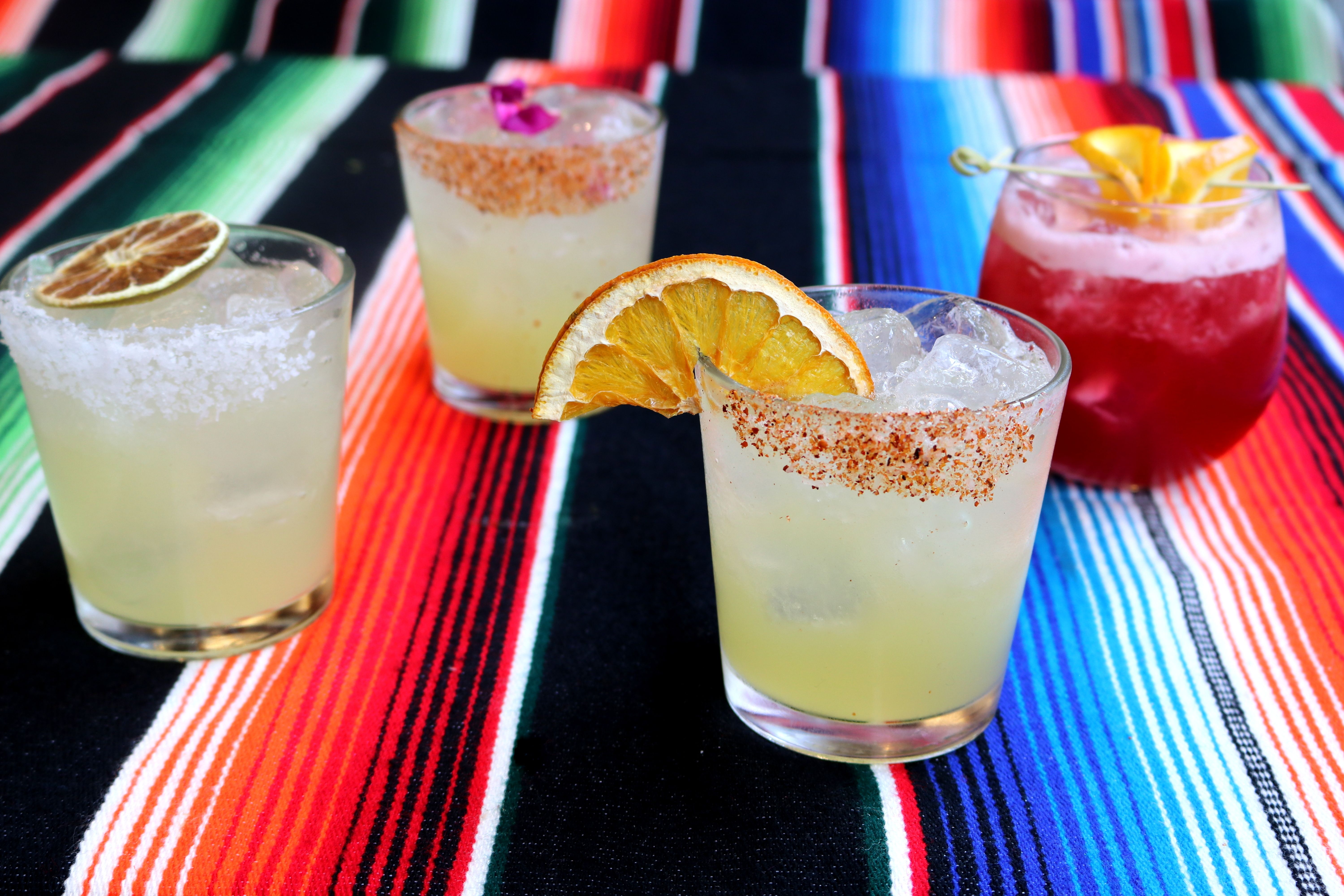 A picture of four Margaritas on top of a table with a Serape