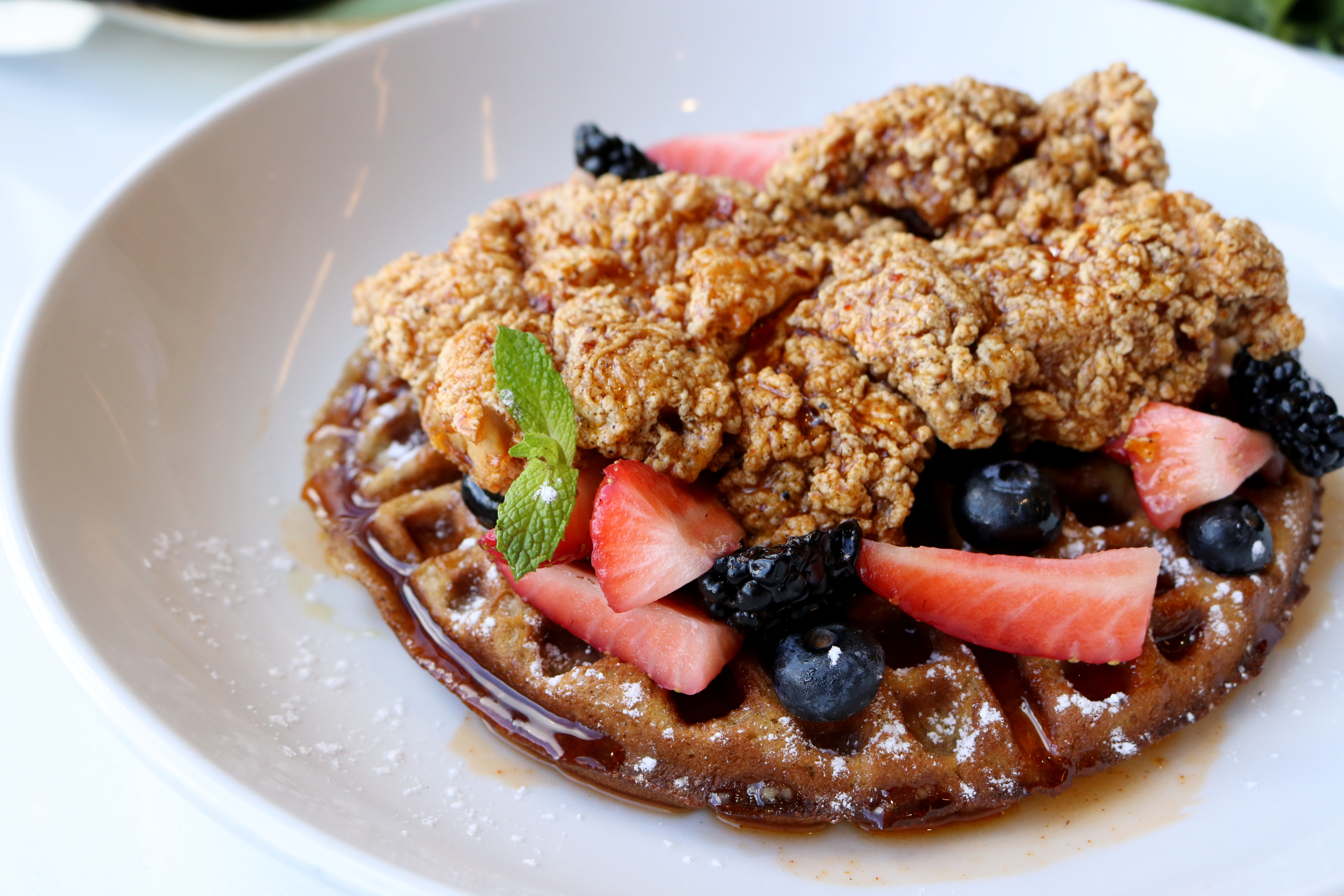 Close up shot of Pollo y Waffle at URBE Houston Street Foods of Mexico at Uptown Parkby Chef Ivan. Food description: cinnamon waffle, guajillo pepper fried chicken, maple, & berries.