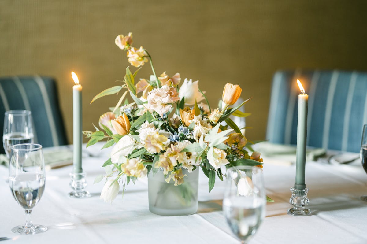 a vase of flowers on a table with wine glasses