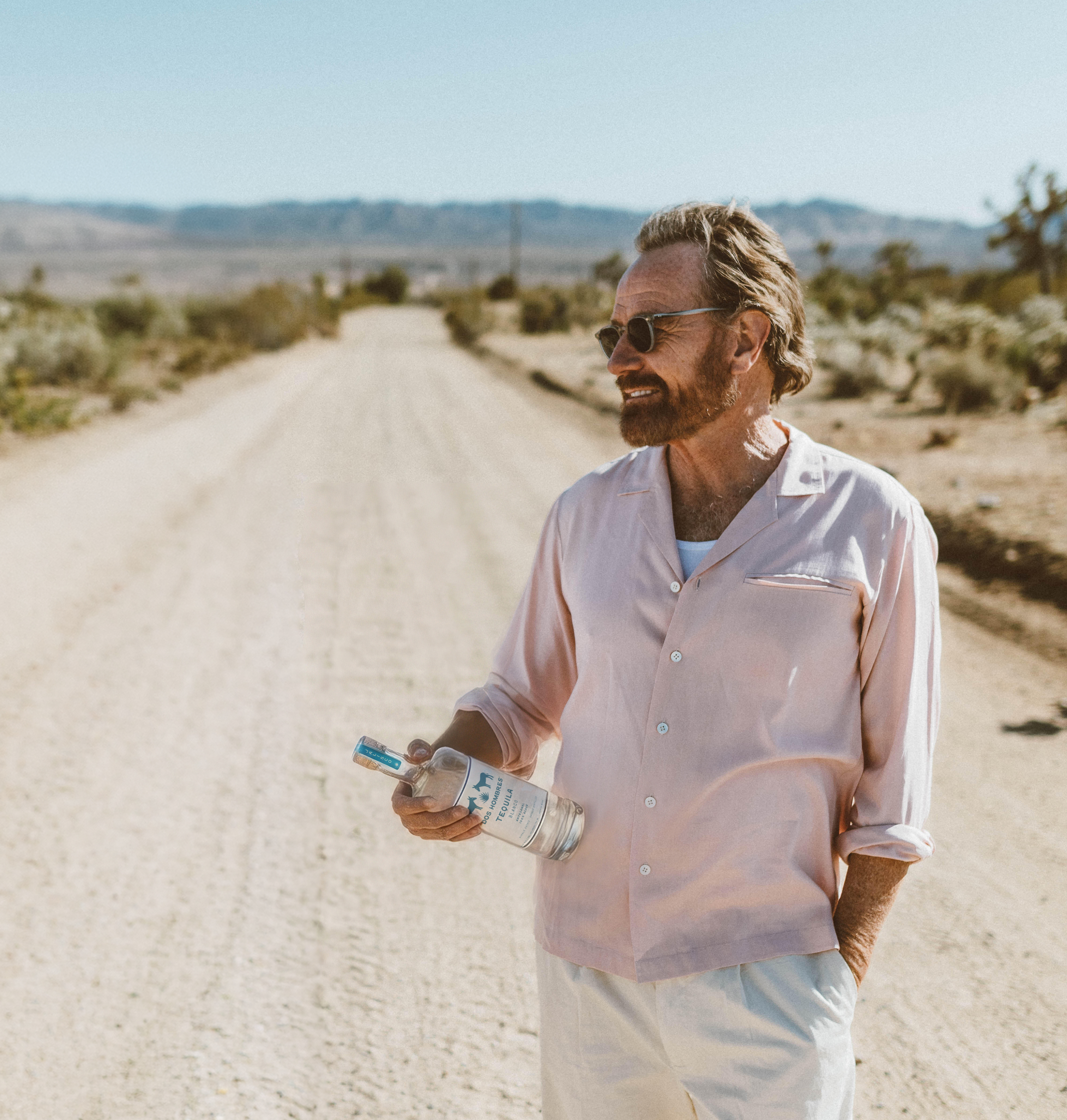 a man standing on a dirt road holding a water bottle