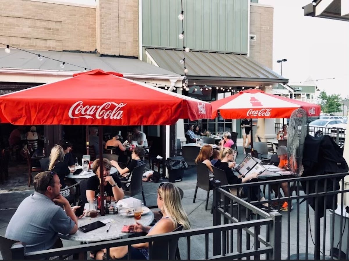 a group of people sitting at a table with an umbrella