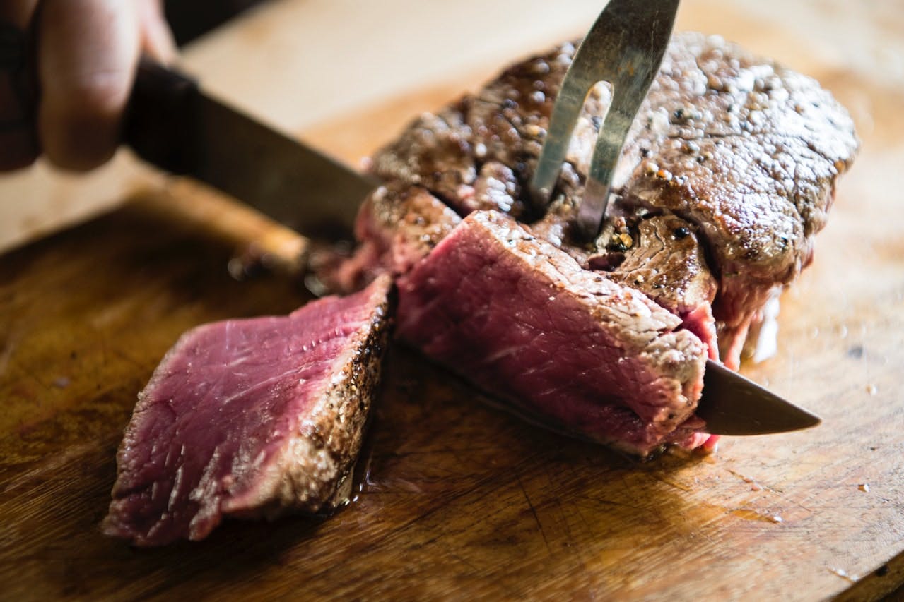 a piece of meat on a cutting board with a cake