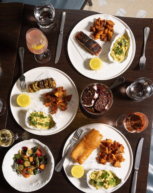 a table with plates of food and glasses of wine