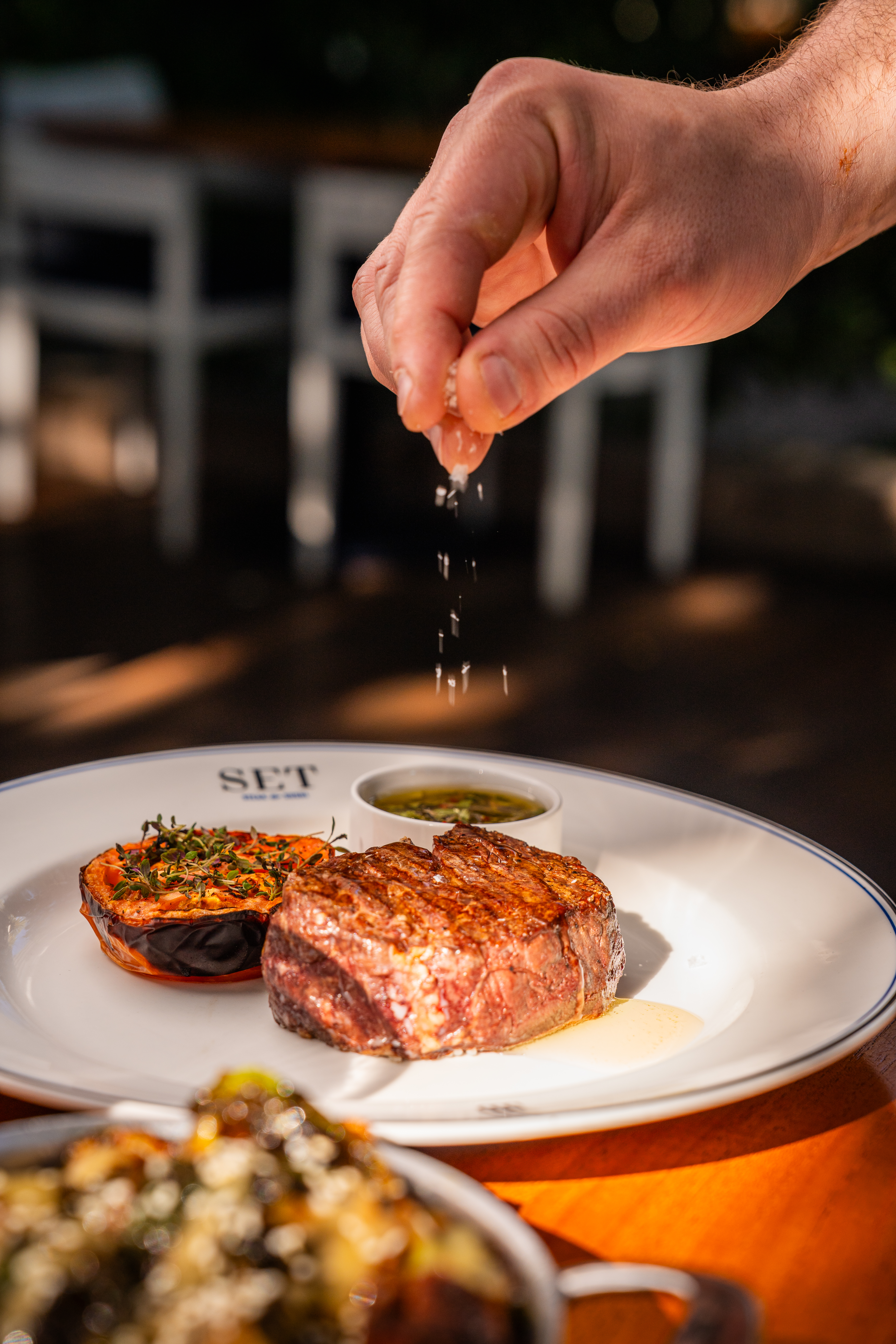 a hand sprinkling salt on a plate of food