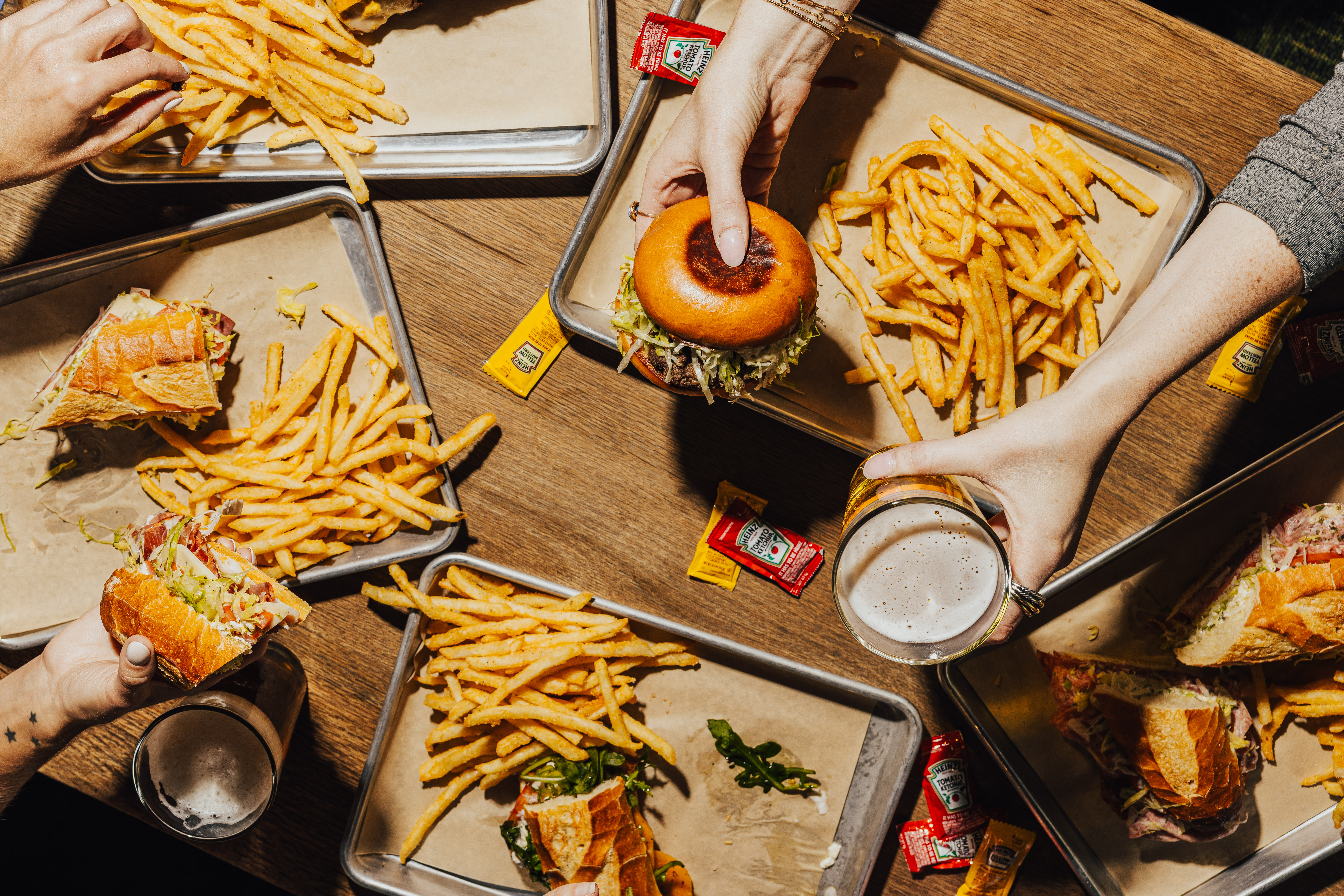 a person holding a burger and fries on trays