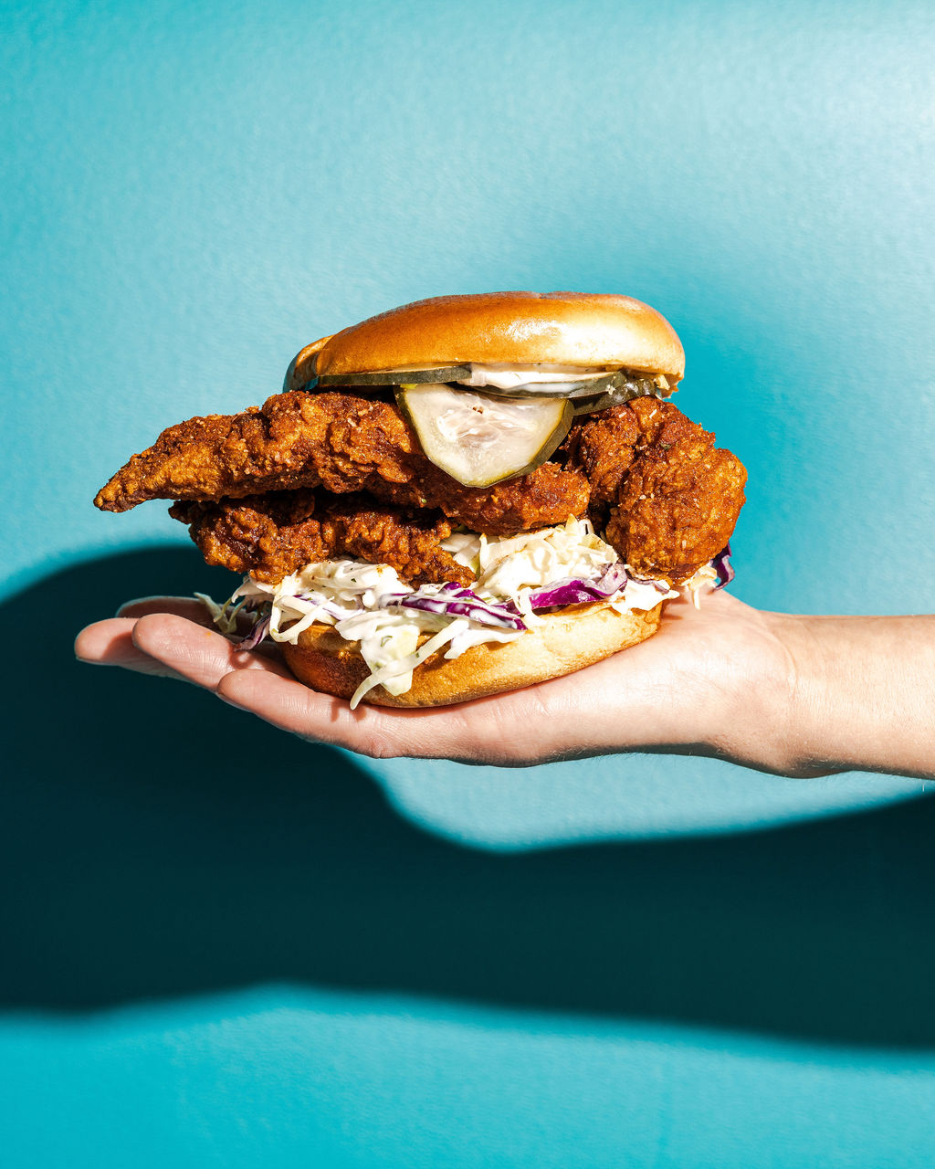 a hand holding a burger