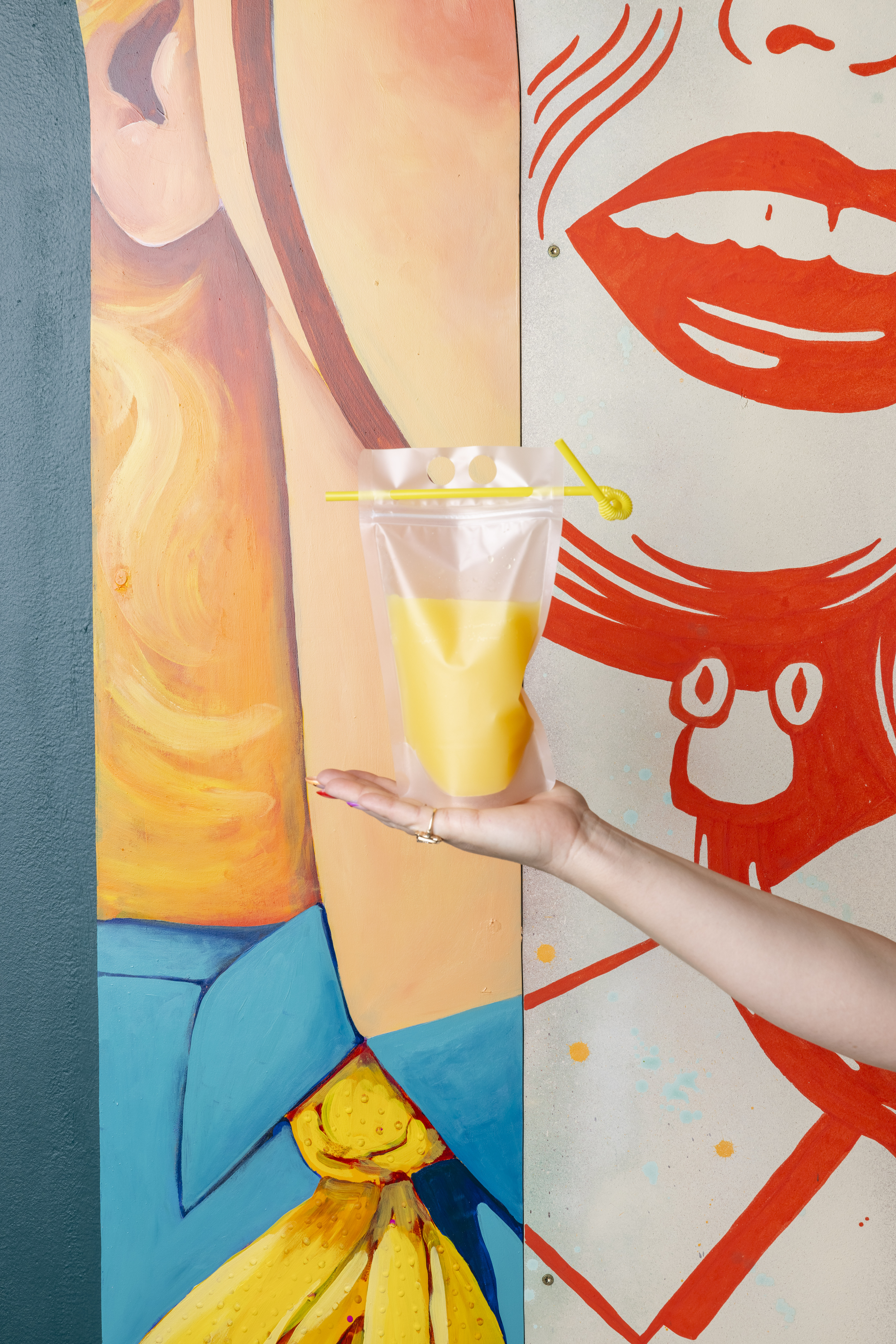 a hand holding a bag of orange juice