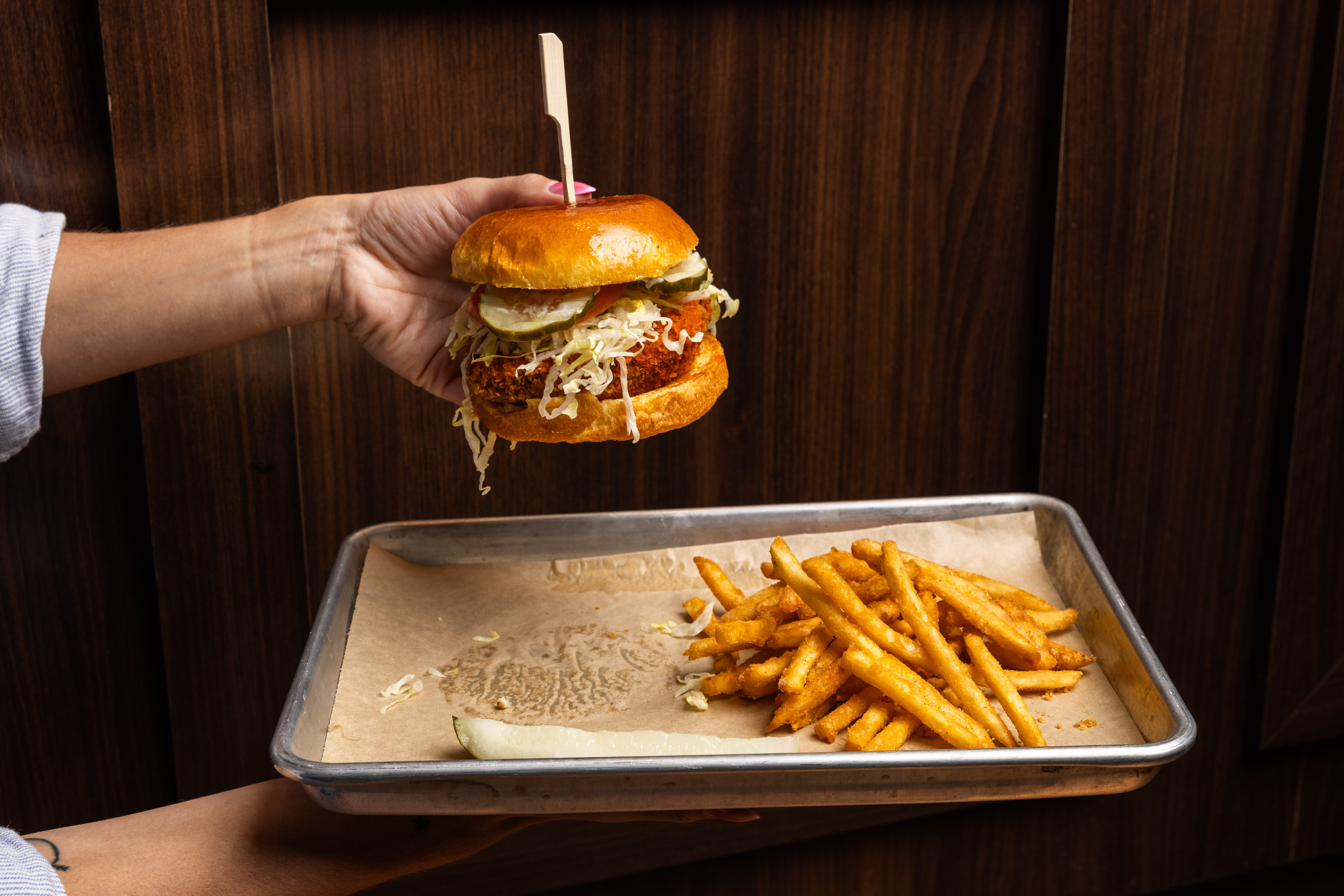 a hand holding a burger and fries