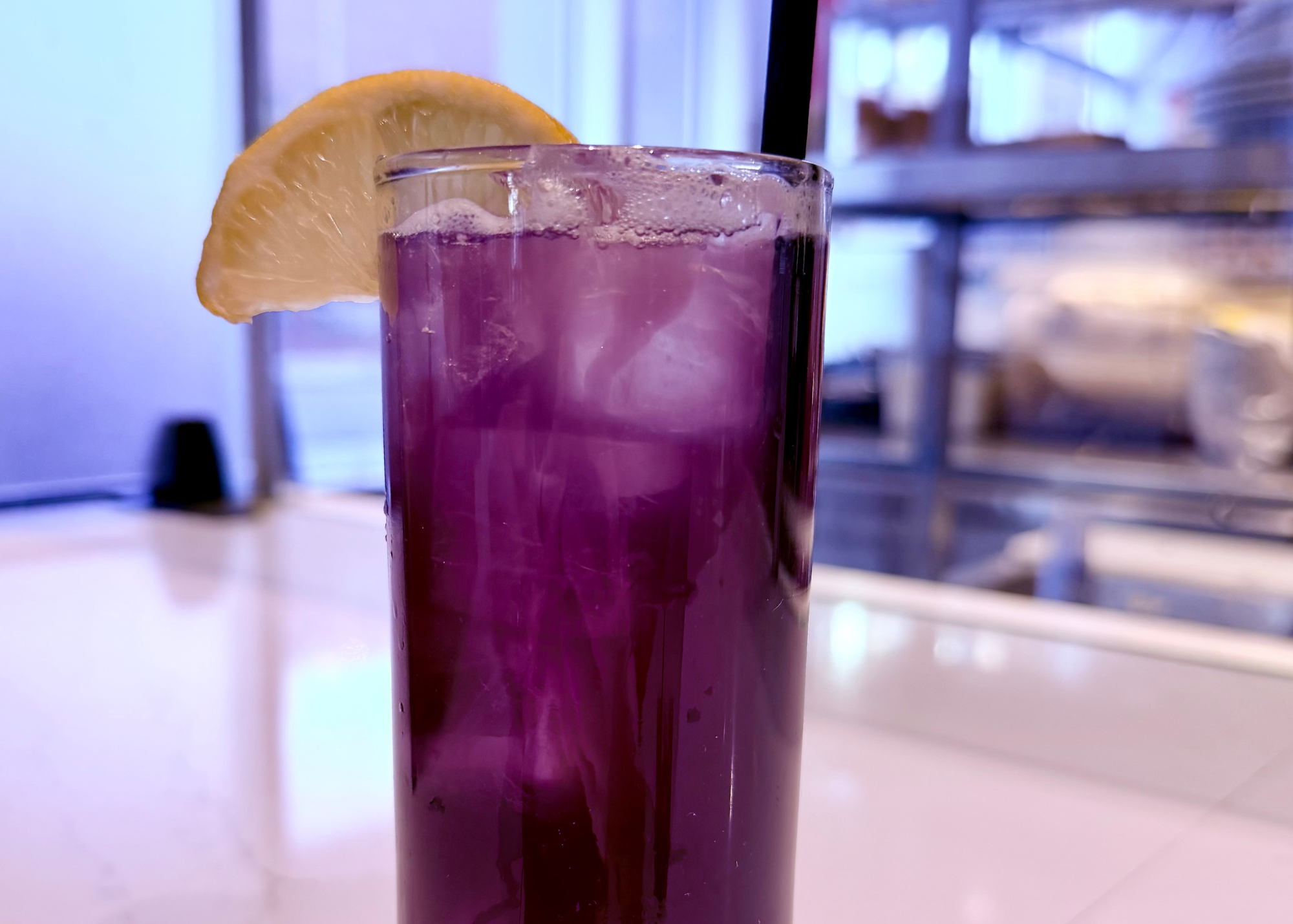 a glass of purple liquid with a slice of lemon