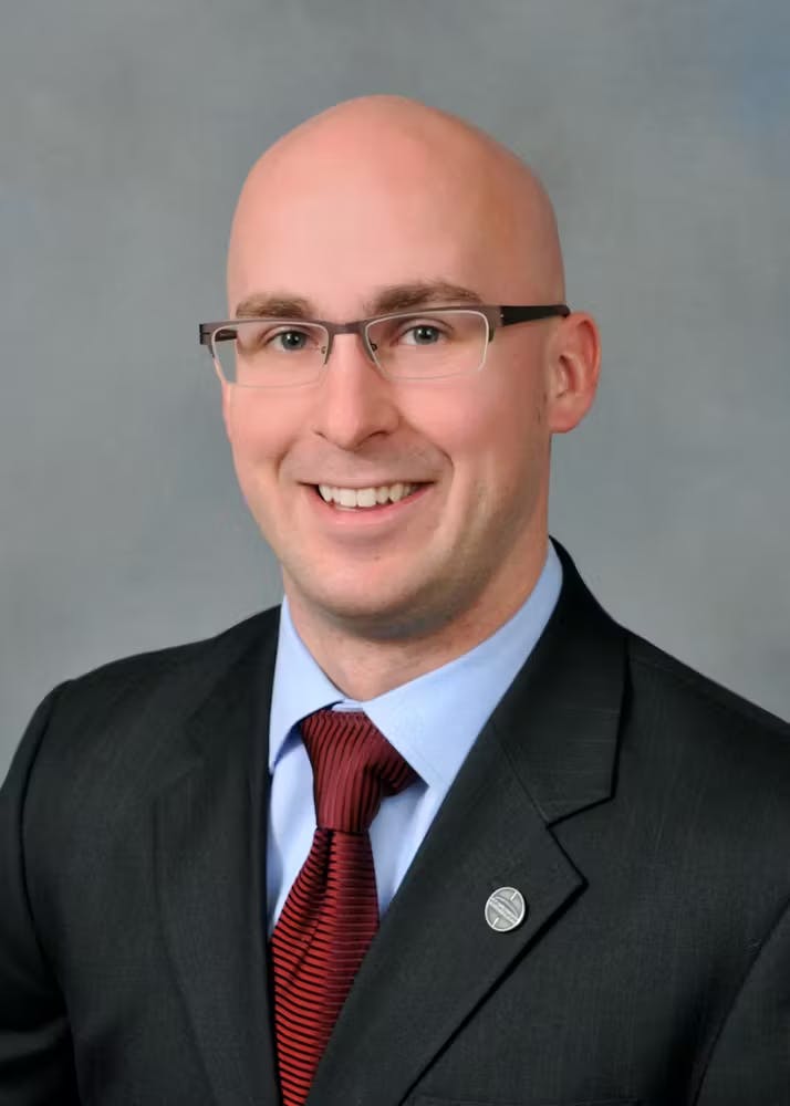 a man wearing a suit and tie smiling at the camera