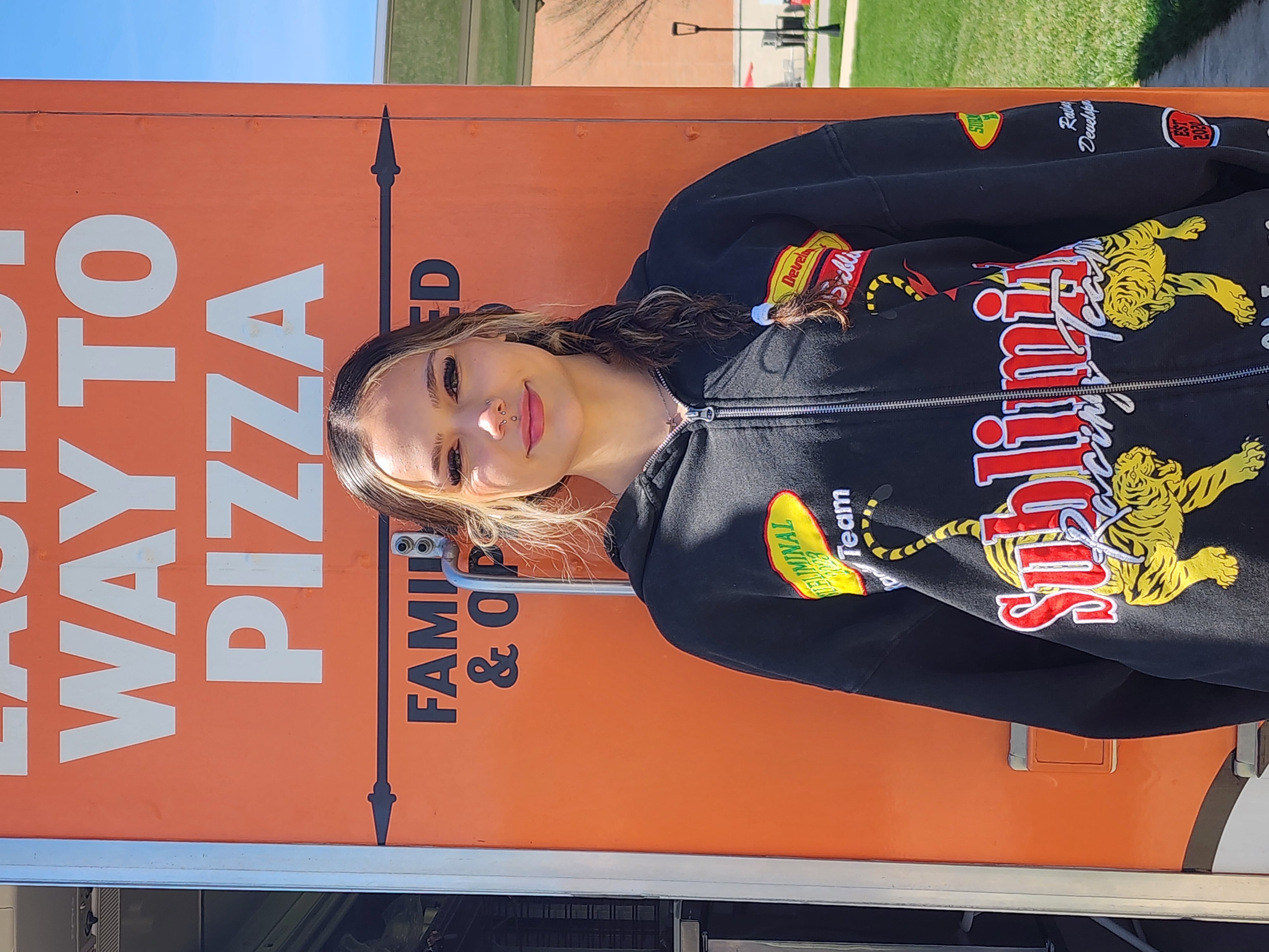 a woman standing in front of a pizza sign
