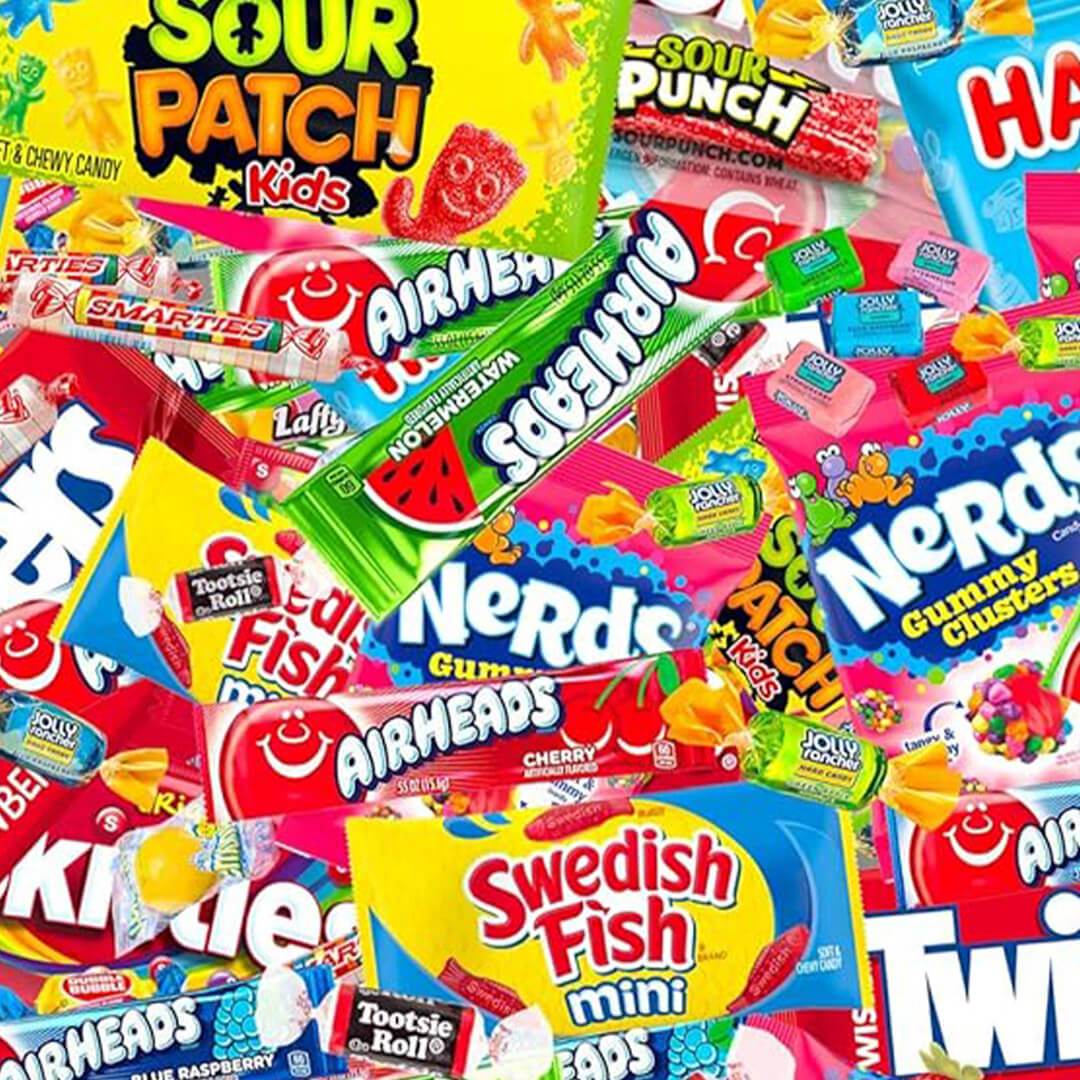 A colorful, dense pile of assorted brand-name candies including Sour Patch Kids, Airheads, Nerds Gummy Clusters, and Swedish Fish.