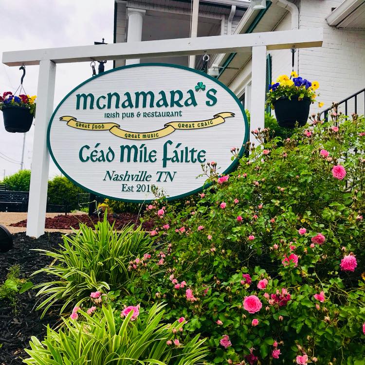 a sign above a flower garden