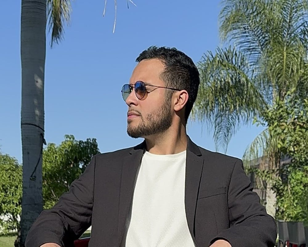 a man wearing a suit and tie standing next to a tree