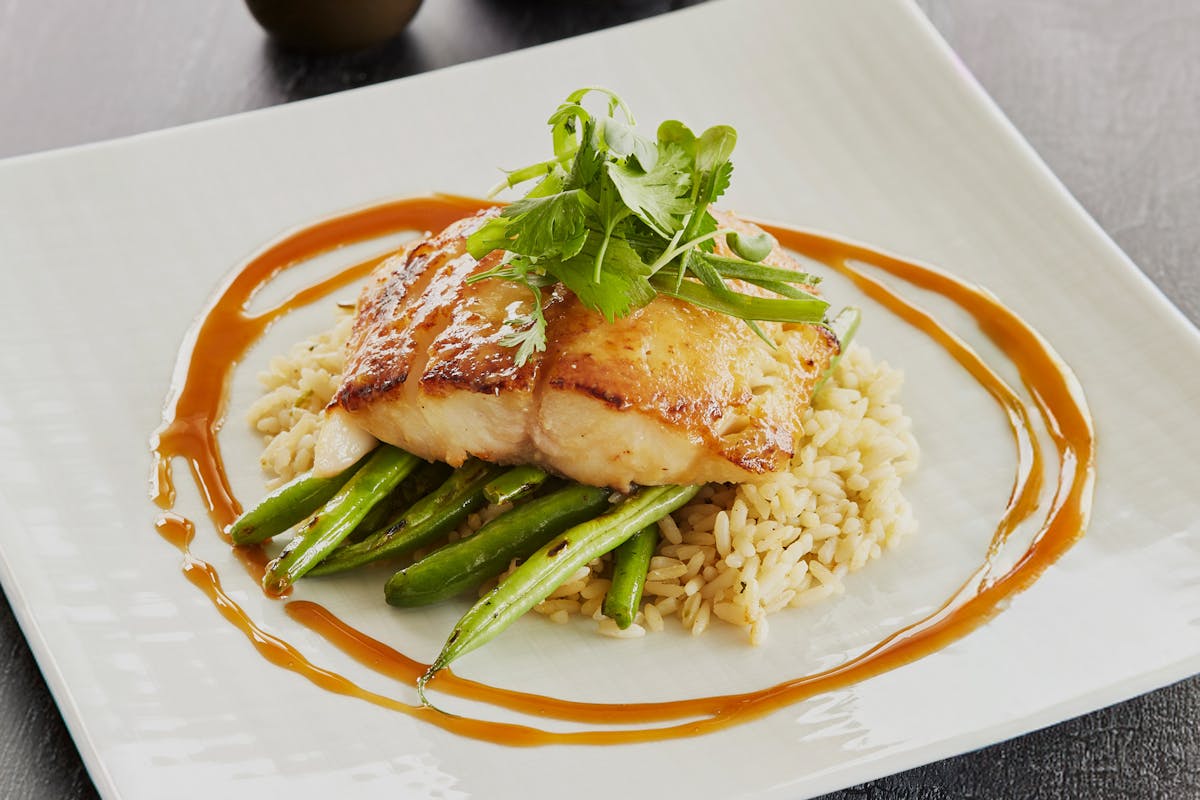 Misoyaki Butterfish Black Cod with a miso glaze served with green beans, coconut rice and eel sauce with green onion and daikon sprouts