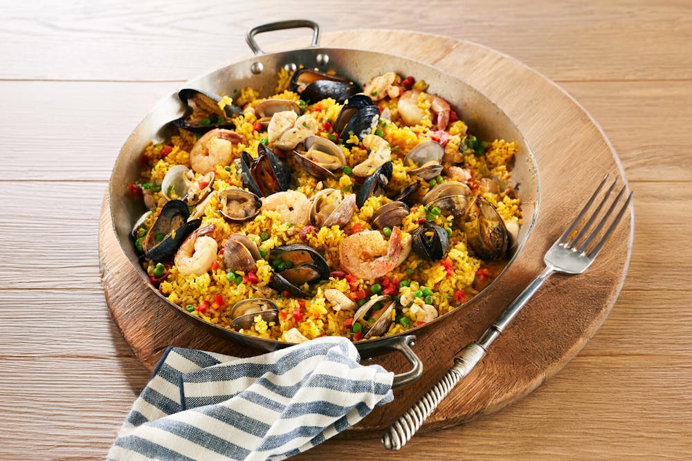 Seafood paella in large serving dishing with fork and napkin