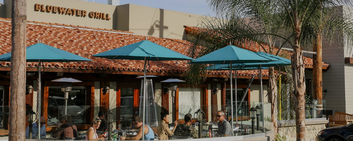 Bluewater Carlsbad front patio with people dining under umbrellas
