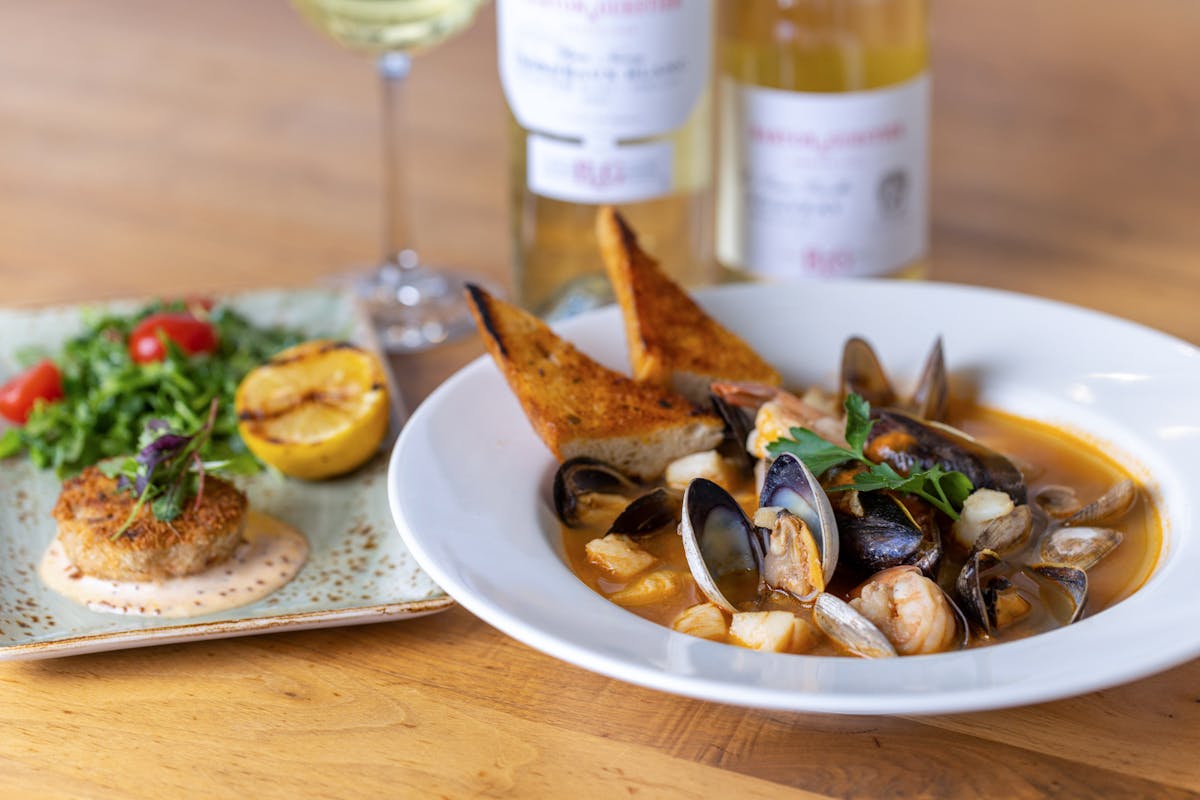 Bouillabaisse and crabcakes with wine in the background