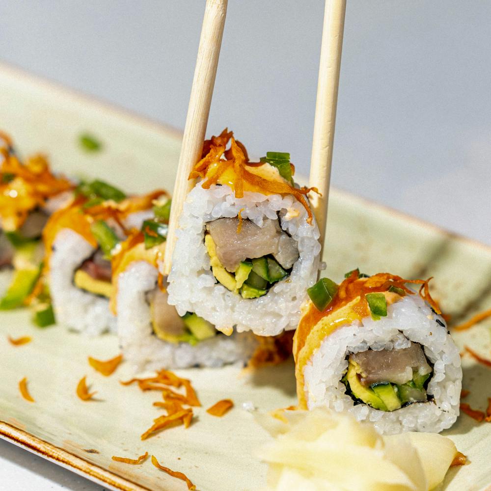 close up of sushi roll being held up by chopsticks