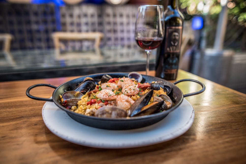 Paella with wine glass and bottle in the background