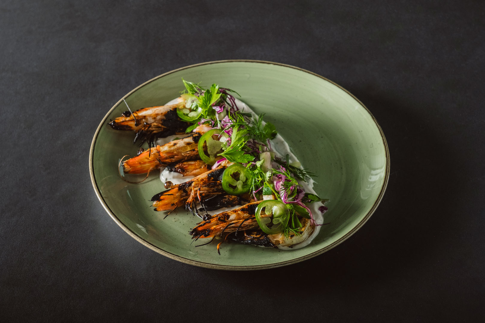 Grilled prawns with Moroccan spice over cucumber, dill yogurt, with jalapeño, red onion, cucumber and fresh-picked herbs