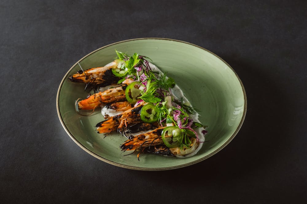 Grilled prawns with Moroccan spice over cucumber, dill yogurt, with jalapeño, red onion, cucumber and fresh-picked herbs