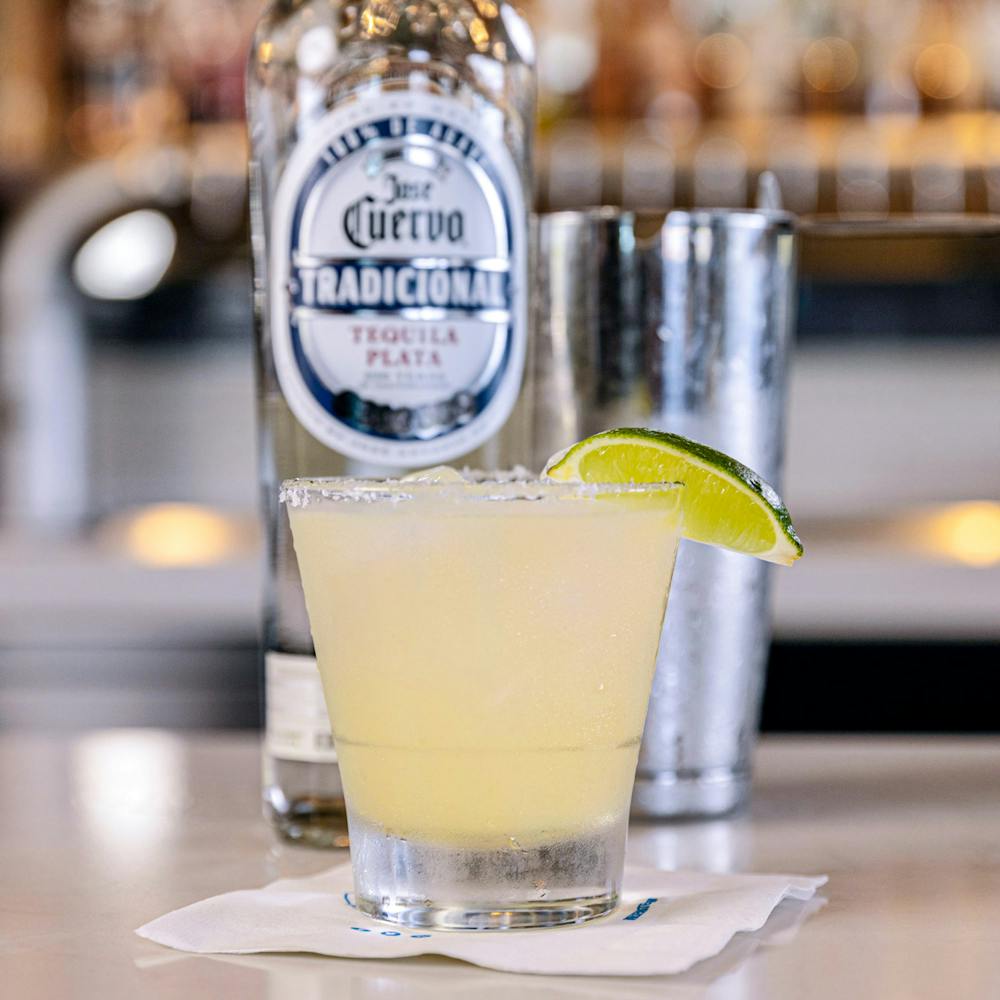 Close up of margarita on napkin with tequila in background.