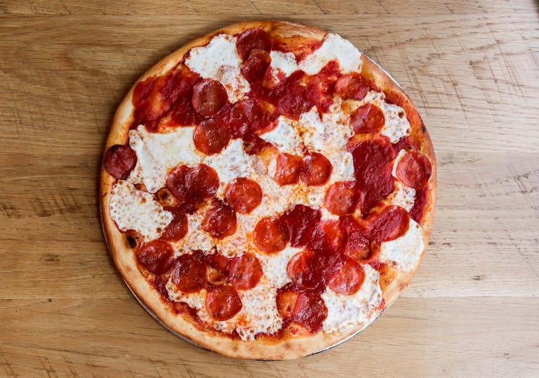a pepperoni pizza sitting on top of a wooden cutting board