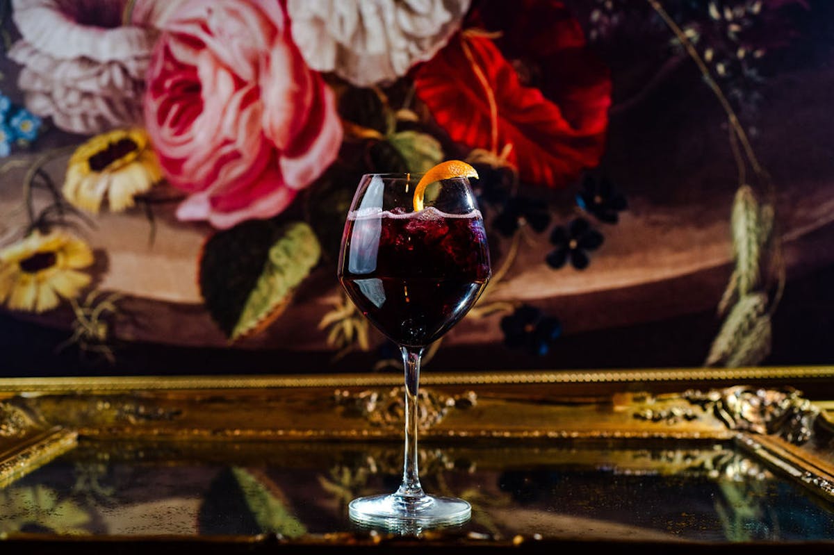 a glass of wine and a vase of flowers on a table