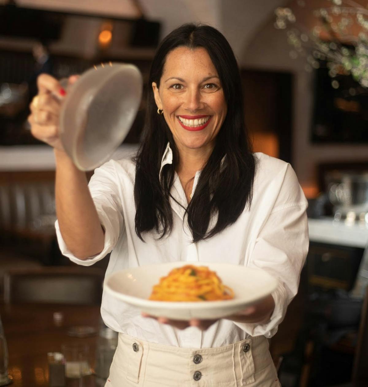 a woman holding a plate of spaghetti