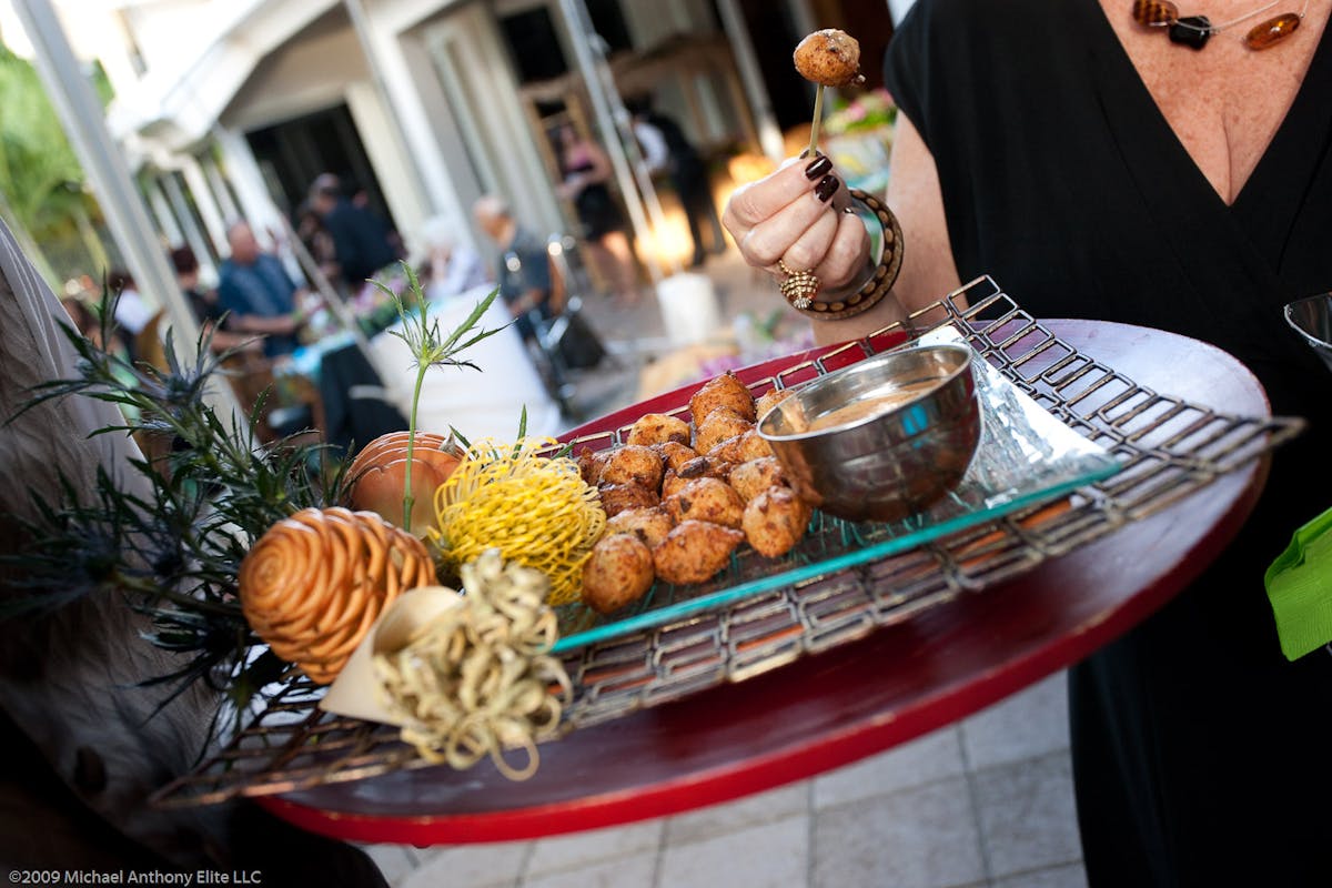 a person holding a plate of food on a table