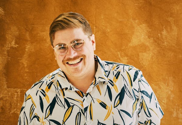 a man wearing glasses and smiling at the camera