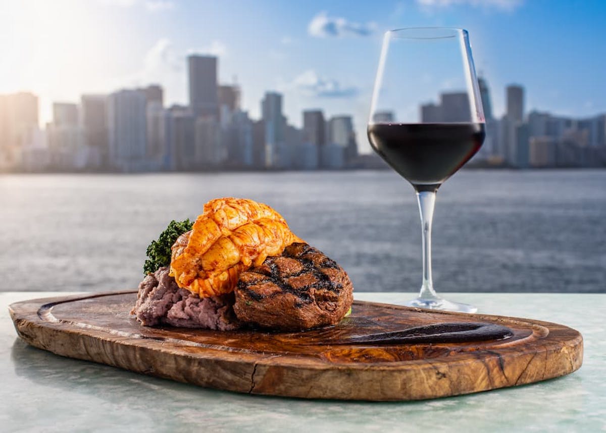 a glass of wine sitting on top of a wooden table next to a steak