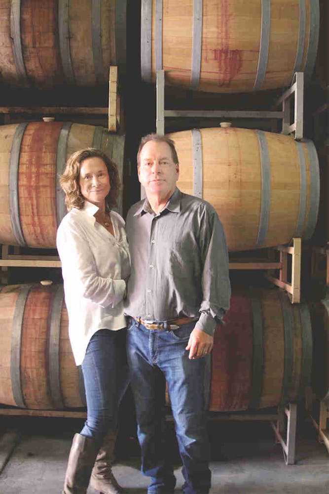 a man and a woman standing in front of a barrel