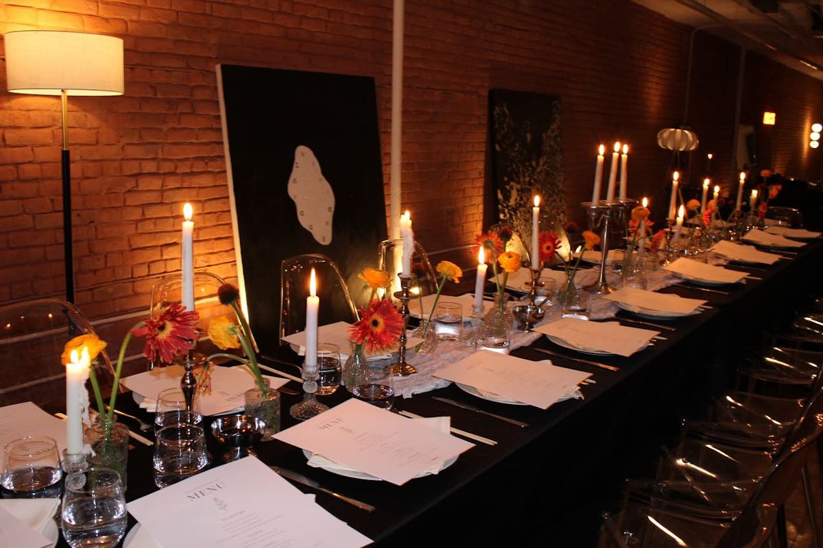 a table with wine glasses in front of a birthday cake with lit candles