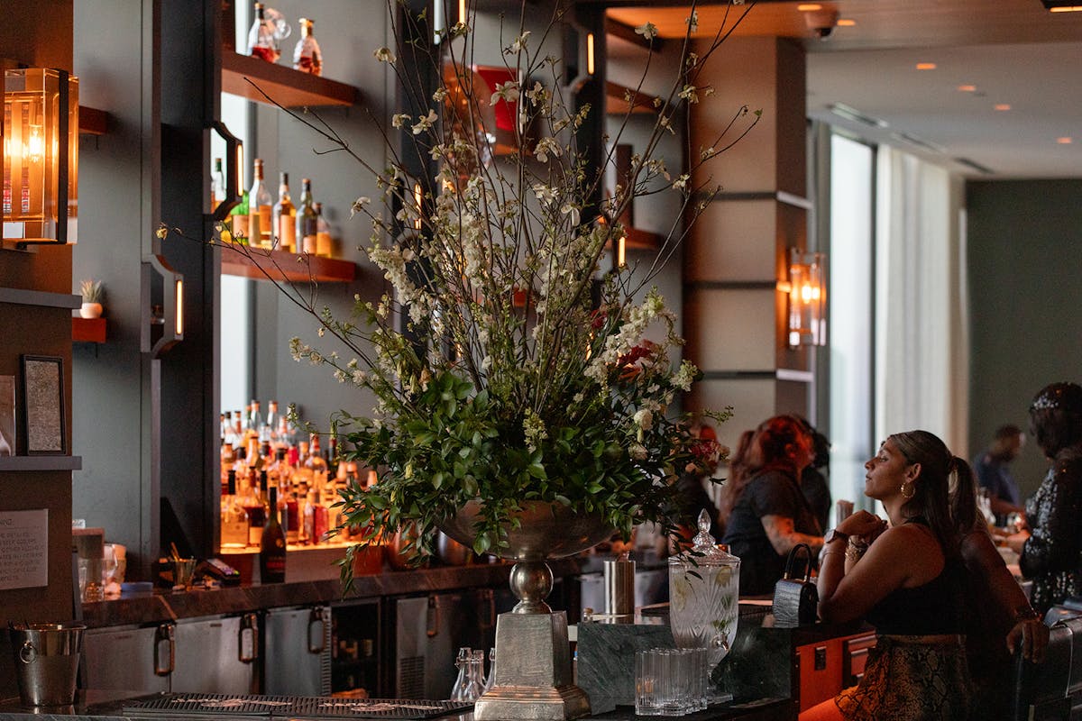 a bouquet of flowers and people sitting at the lively bar at tesserae