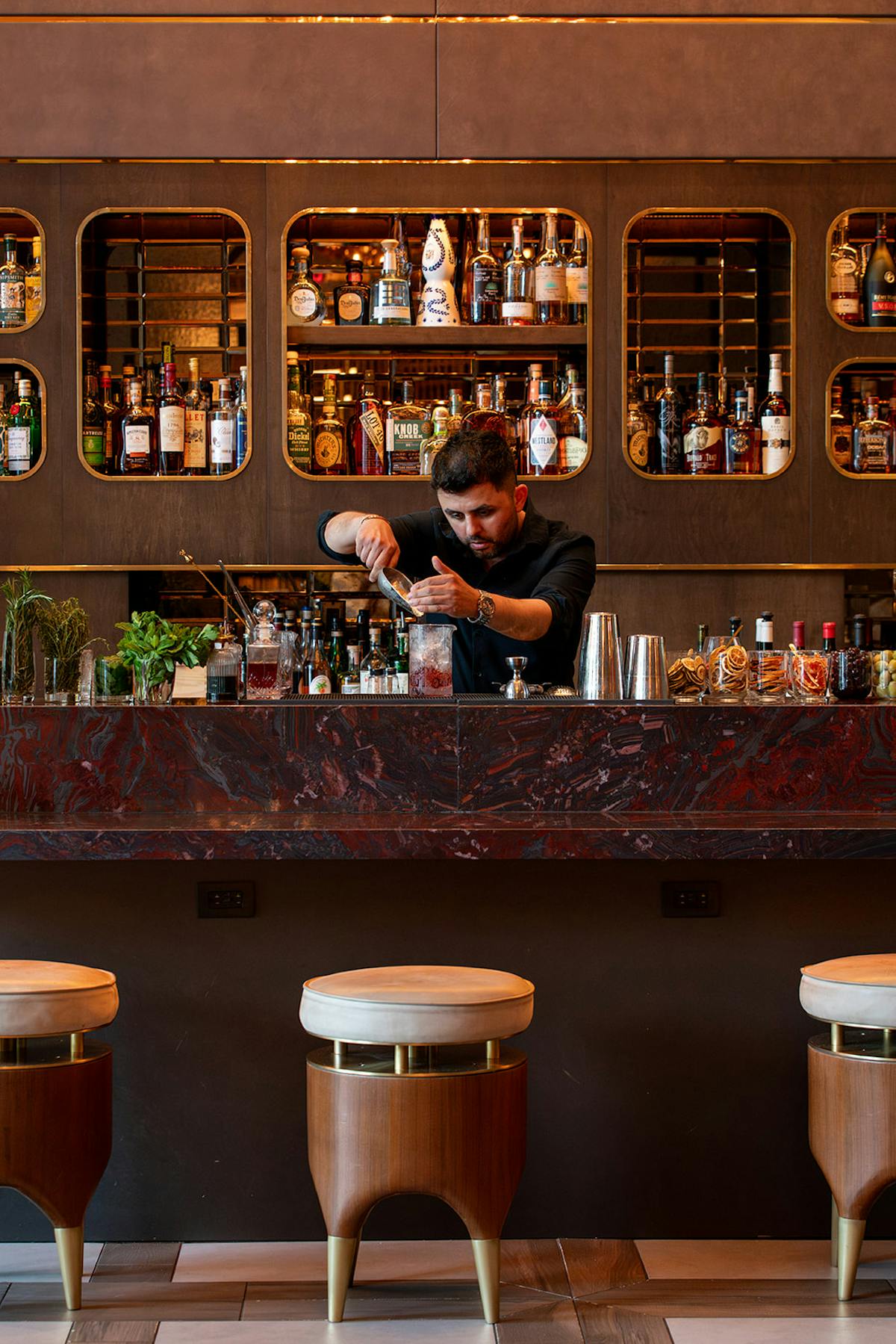 a bartender pouring ice into a cocktail shaker at tesserae lounge