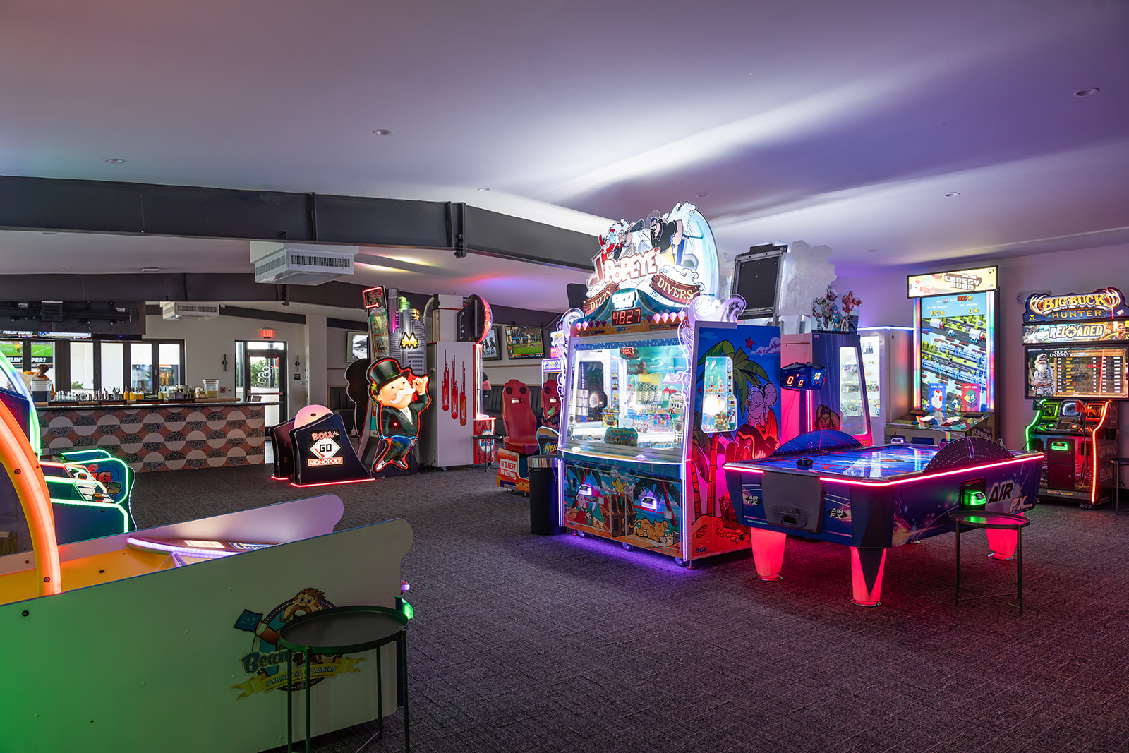 a groupArcade games and air hockey inside 1983, a Tampa arcade bar with classic games, sports TVs, and a lively nightlife atmosphere. of people in a room