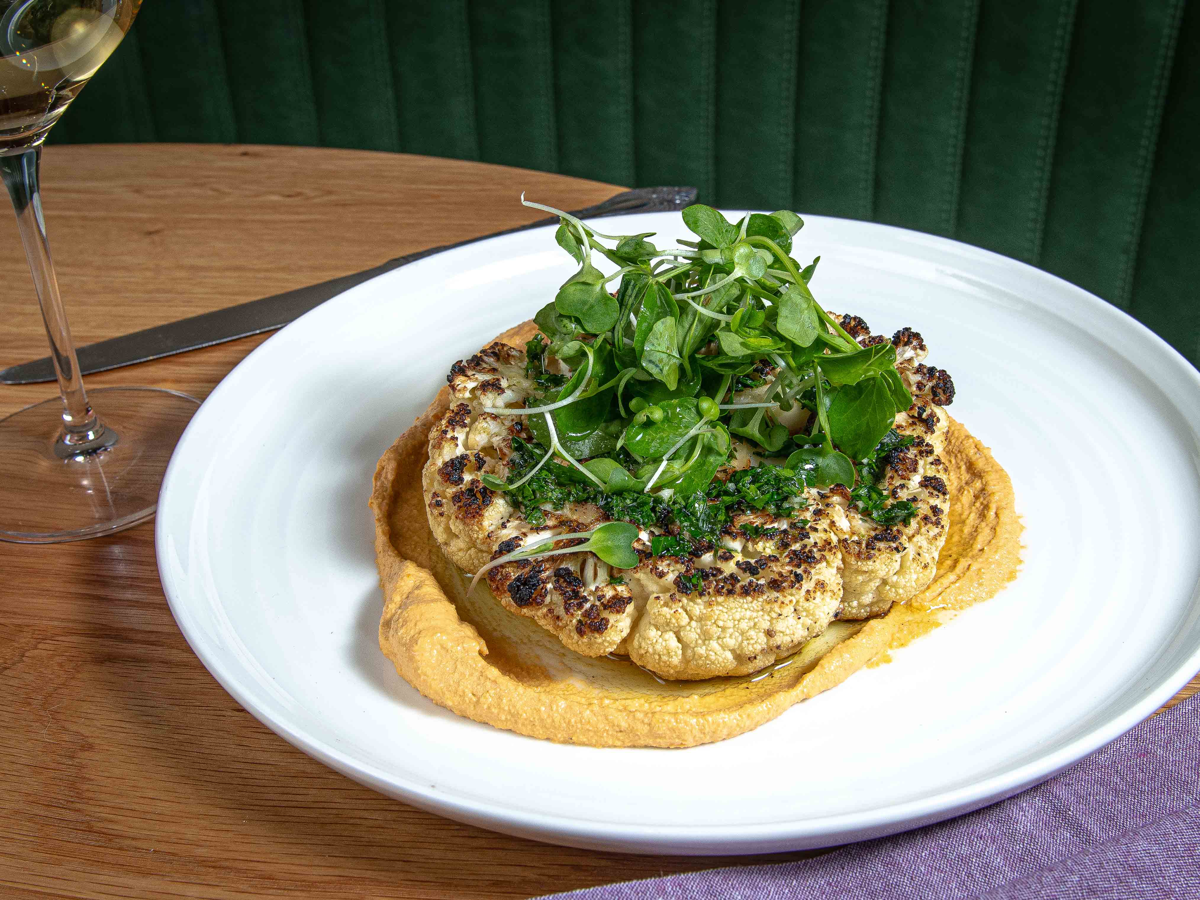Charred cauliflower steak with tomato almond sauce & chimichurri. Vegan entree at Jackie Restaurant, American bistro in Navy Yard, Washington DC.