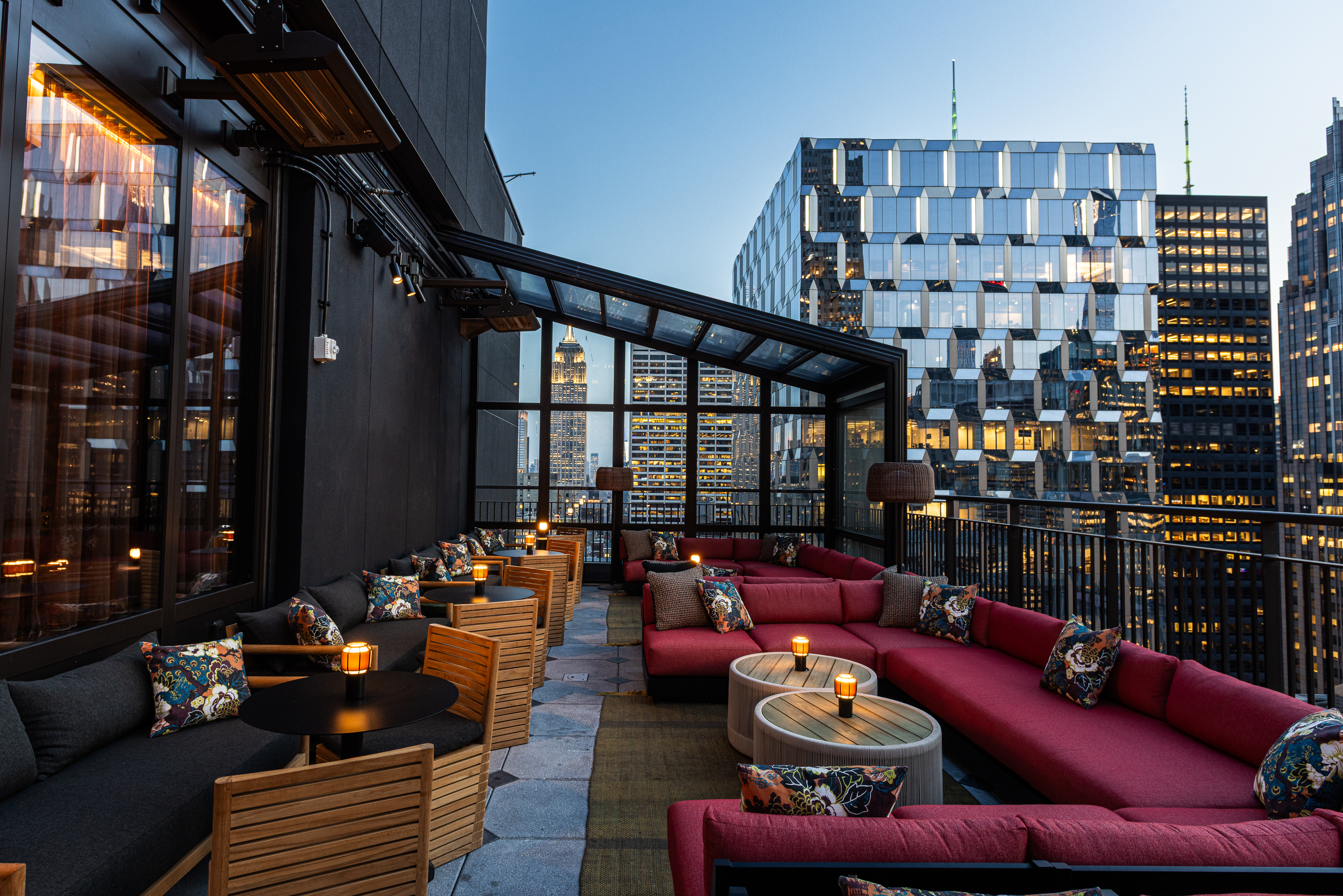 a rooftop patio with tables and chairs and a glass building in the background