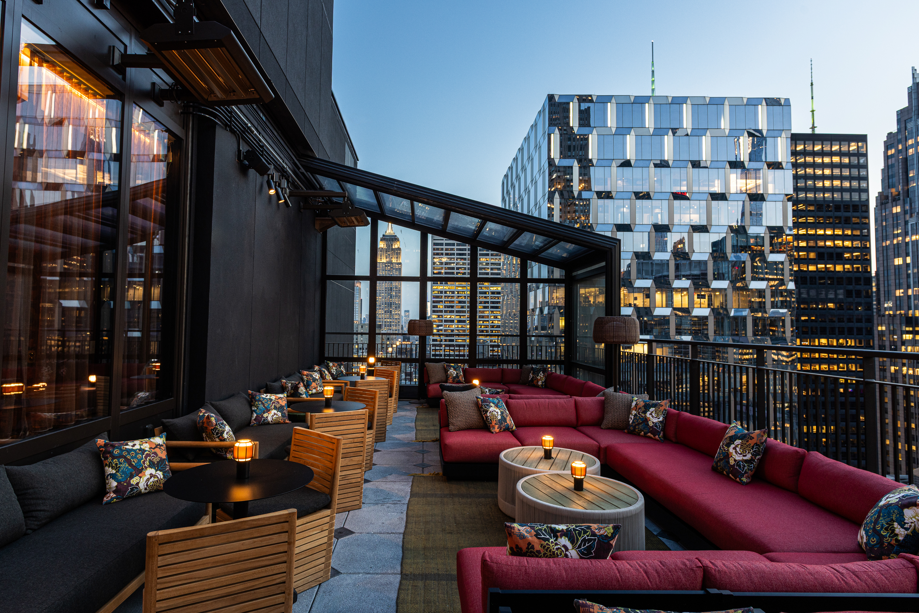 a rooftop patio with tables and chairs and a glass building in the background