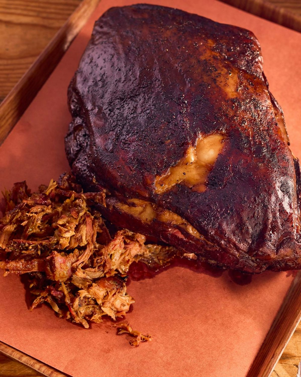 Smoked pork shoulder with a pile of pulled pork on butcher paper