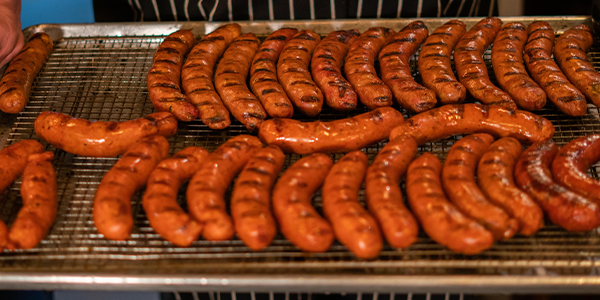 a bunch of hot dogs cooking on a grill
