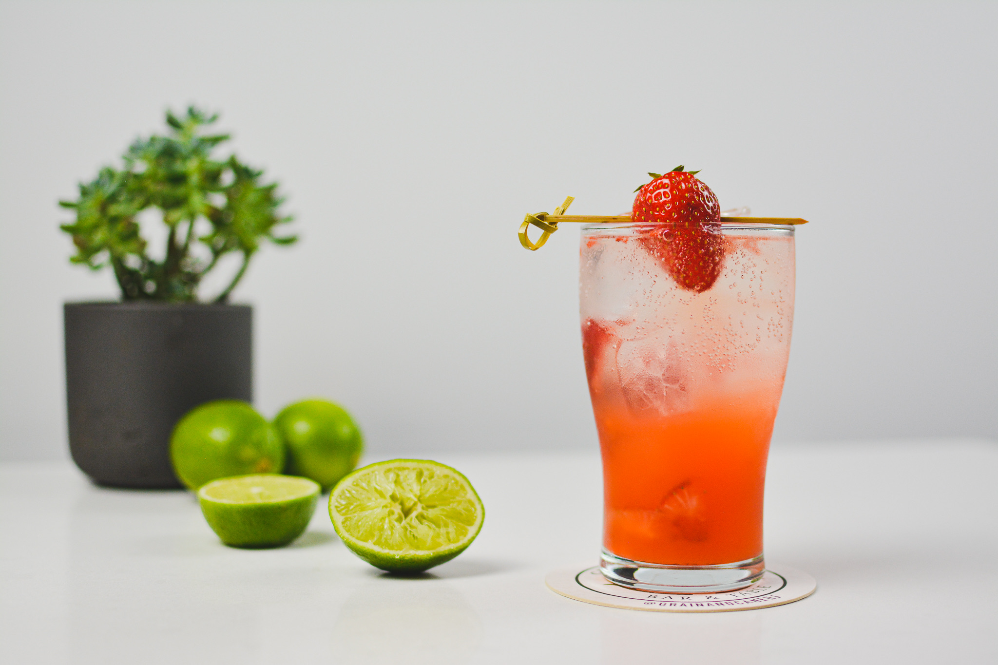 a close up of strawberry mocktail on table with lime halfs