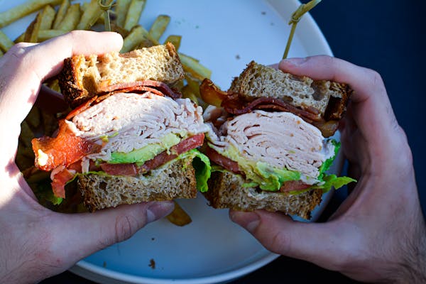 a hand holding a half eaten sandwich on a plate
