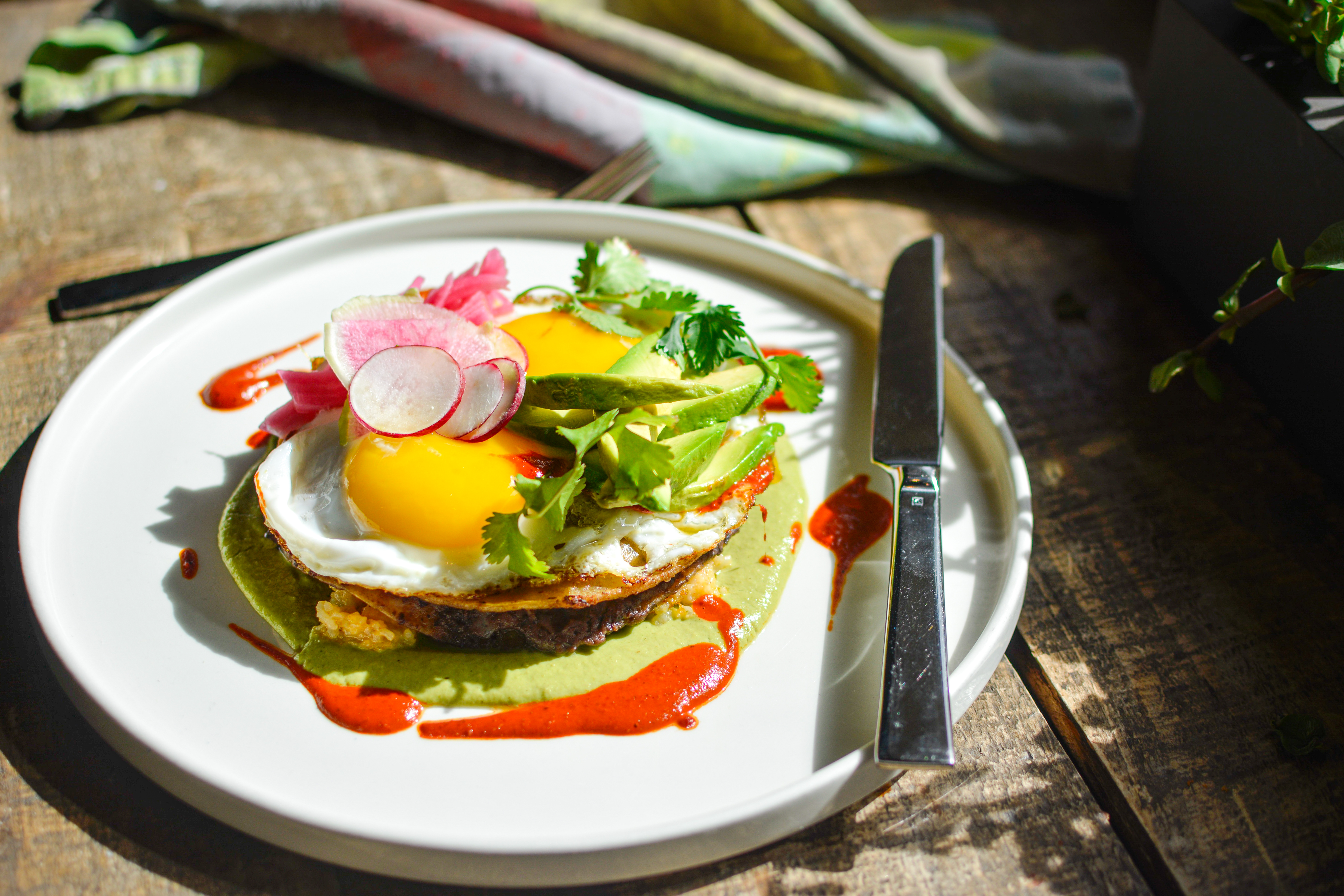a close up of a sald wtih egg yolk on a plate with a knife on the side 