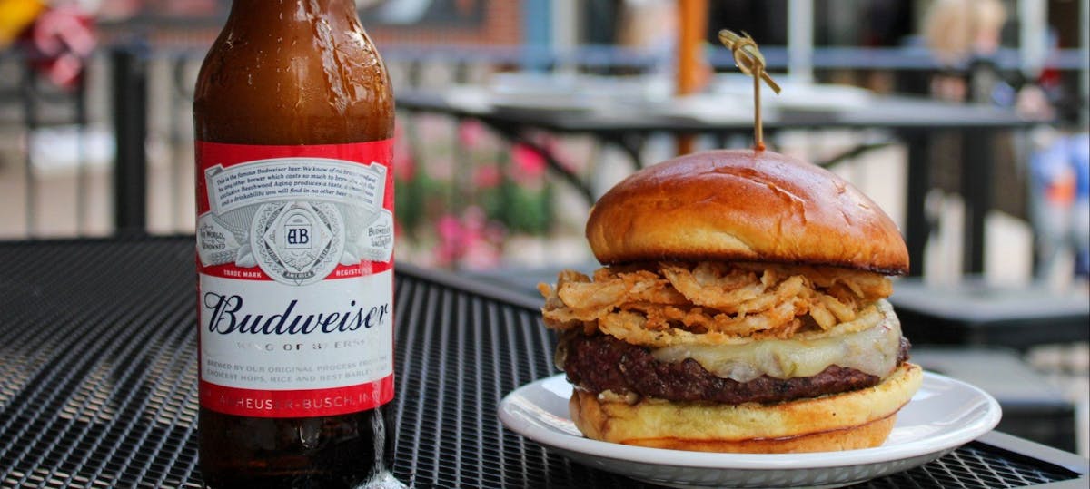 a close up of a bottle and a burger on a plate