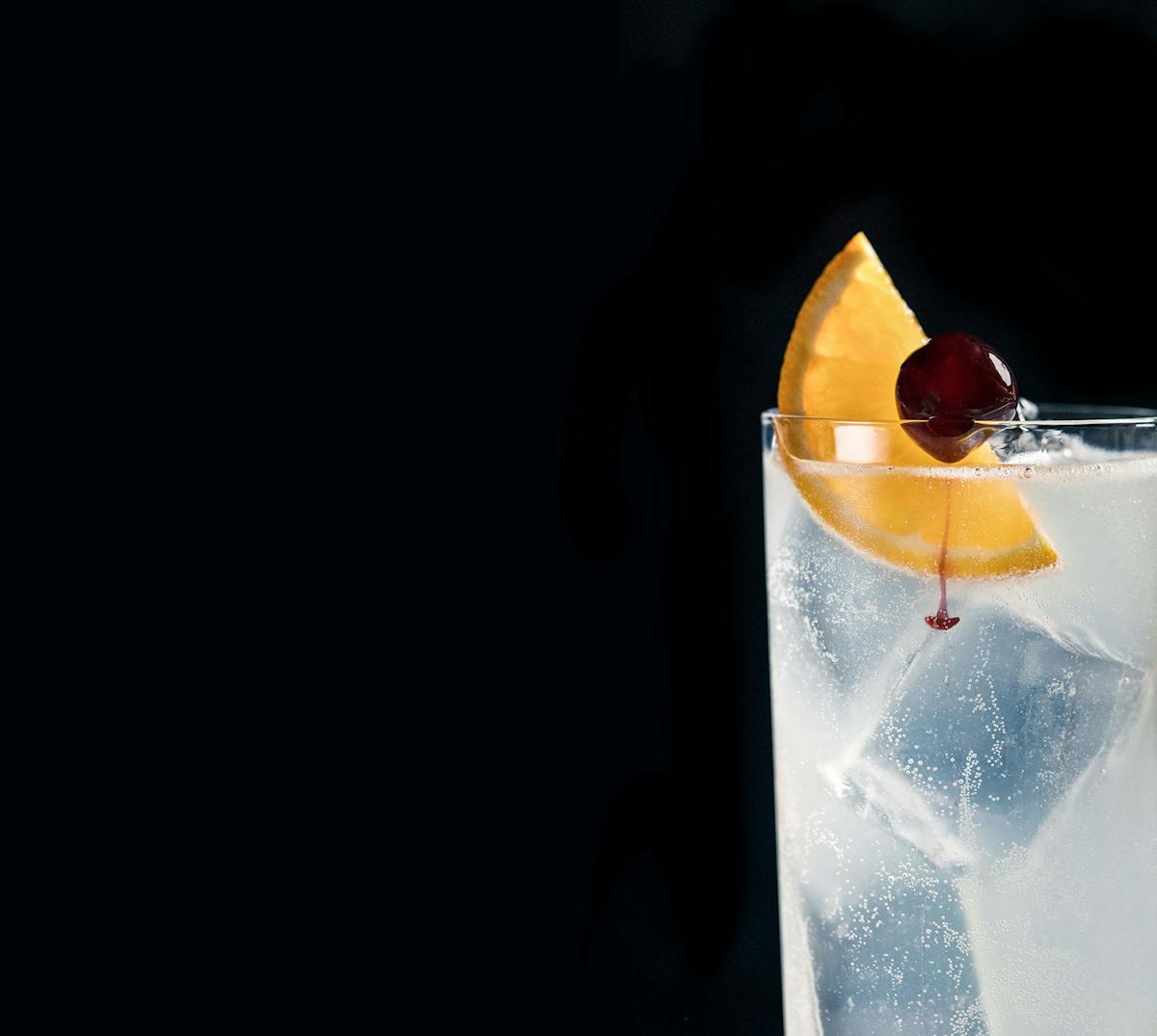 a cocktail served on a glass with an orange slice and a cherry