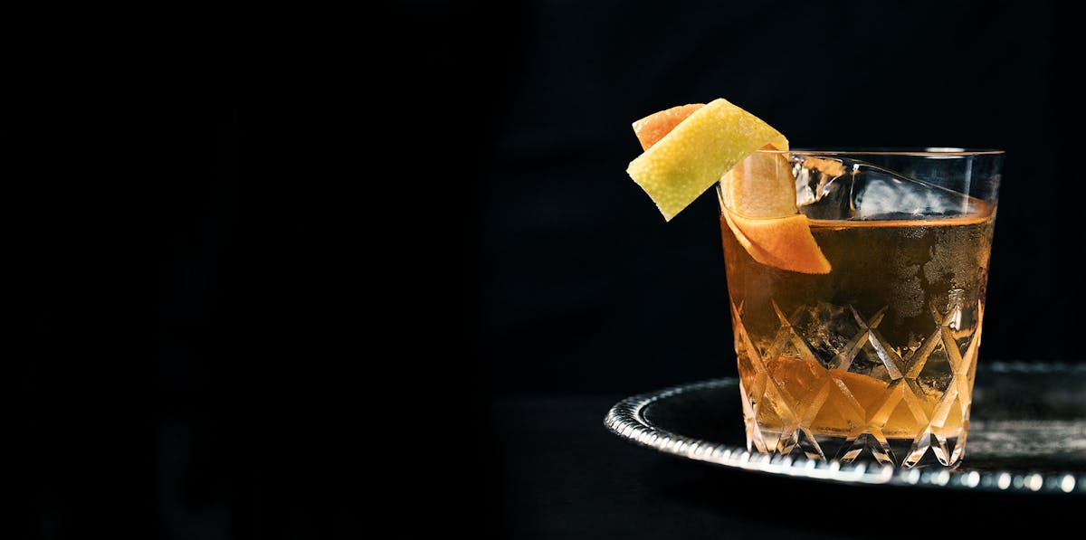 a cocktail glass with a slice of fruit